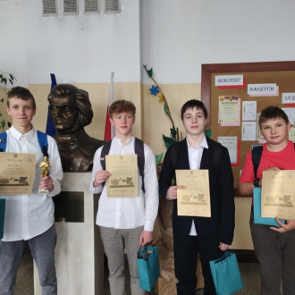 Nagrodzeni uczniowie z dyplomami, w tle popiersie Adama Mickiewicza