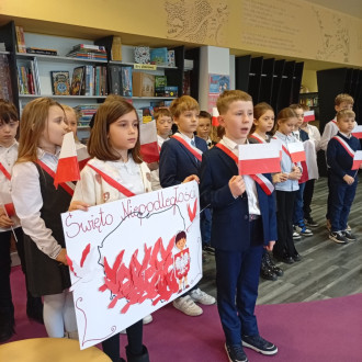 uczniowie podczas występu z flagami narodowymi