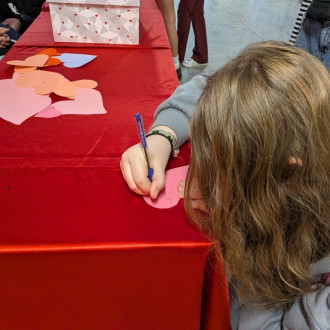 Uczennica pisząca tekst na serduszku walentynkowym