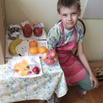 Uśmiechnięty uczeń przy stole z owocami