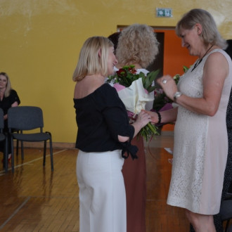 Rodzice składający kwiaty dyrekcjom, w tle nauczyciel wspomagający