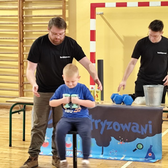 uczeń siedzi z ciężarkami w rękach na krześle żyroskopowym