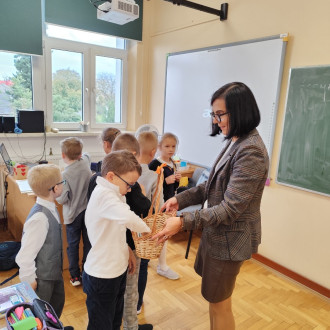 pani dyrektor rozdaje uczniom kl. 1b emblematy szkoły