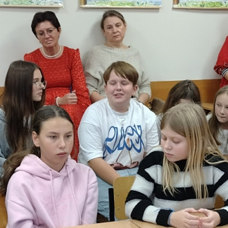 Uczeń klasy piątej podczas wypowiedzi, w tle nauczyciele i inni uczniowie