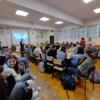 Uczniowie i nauczyciele podczas debaty, w tle prezentacja o prawach dziecka